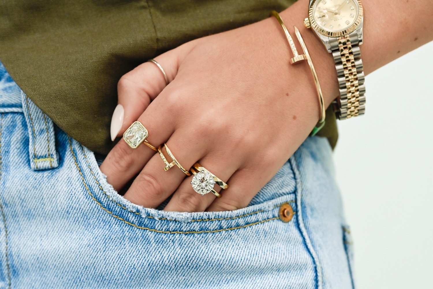 A woman's hand in a pocket wearing several rings, a bracelet and a watch.