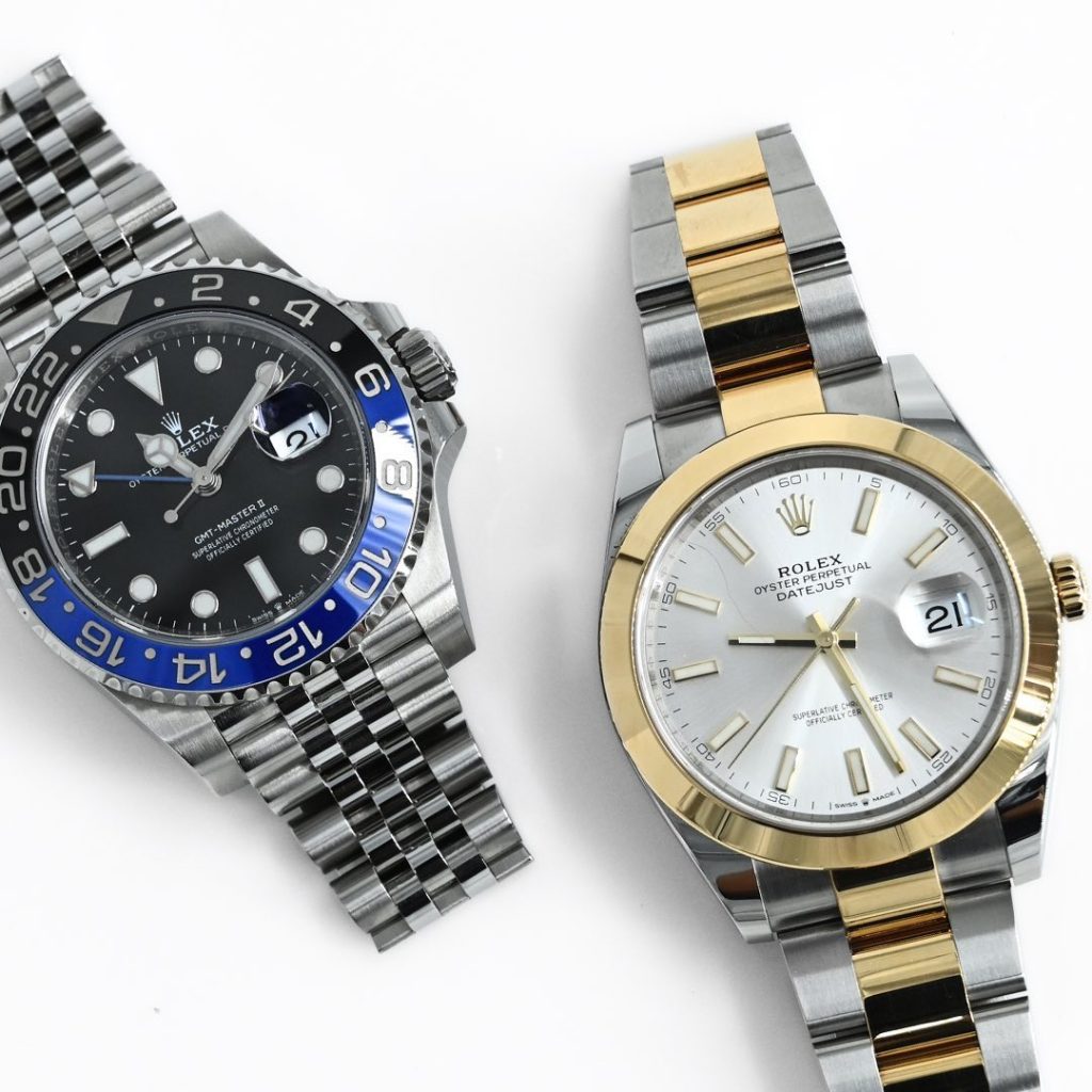 Two Rolex wristwatches: one with a black and blue bezel on a silver bracelet, and one with a gold and silver bracelet and a white face.