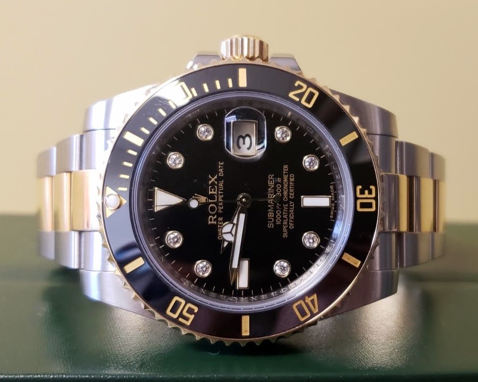 A close-up of a Rolex Submariner wristwatch with a black dial, gold accents, and a metal bracelet displaying the date as 3—perfect for those looking to pawn Rolex in Boca Raton.